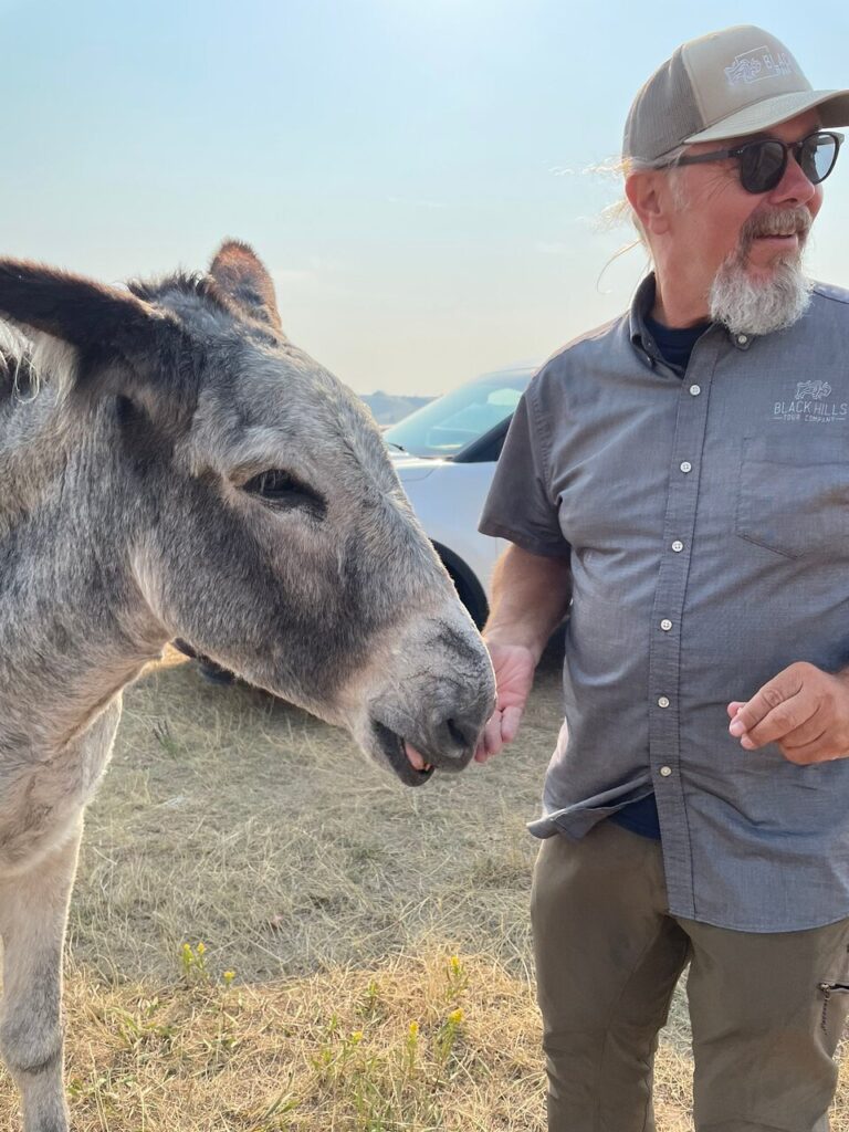 Black Hills Tour Company tour guide petting donkwy